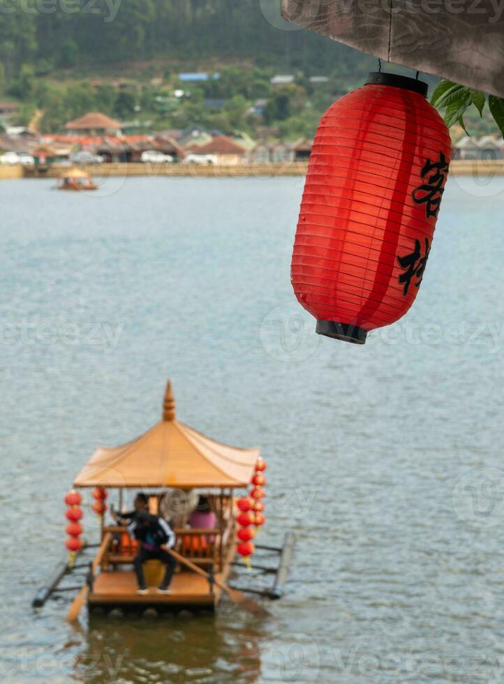 lanternas chinesas e barcos no lago com pôr do sol sobre ban rak thai foto