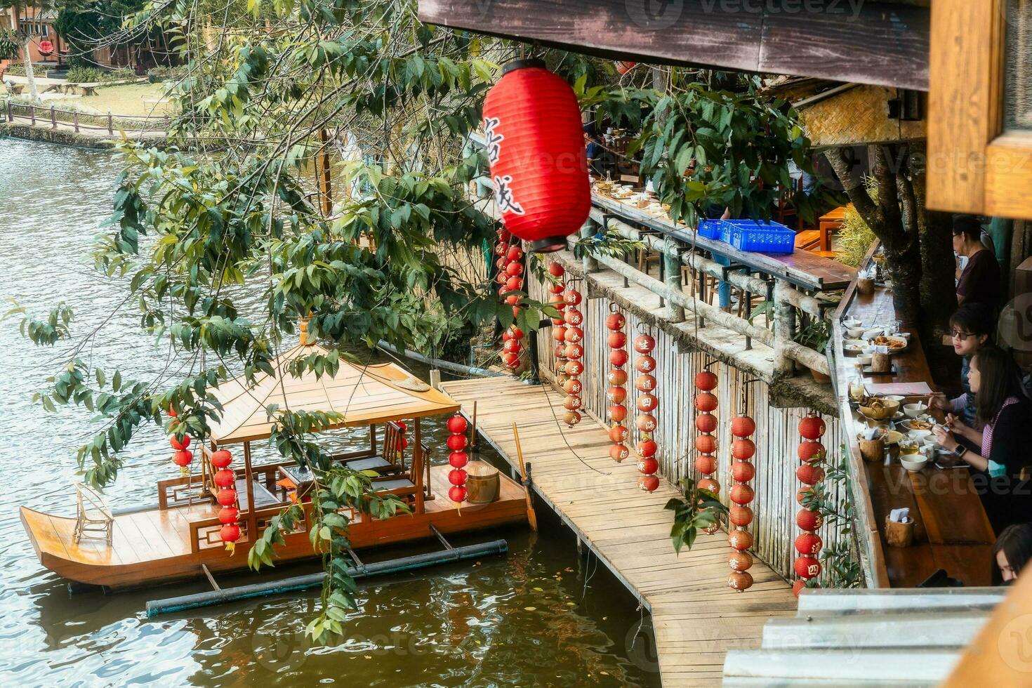 lanternas chinesas e barcos no lago com pôr do sol sobre ban rak thai foto