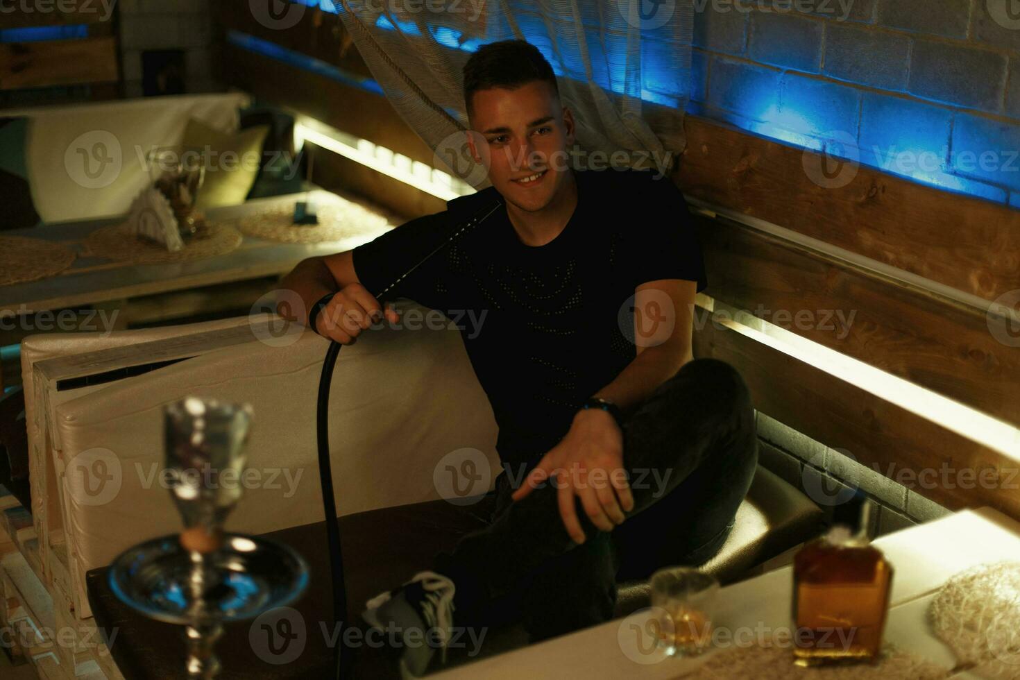 bonito hipster cara relaxante dentro a bar. homem fuma uma cachimbo de água. foto