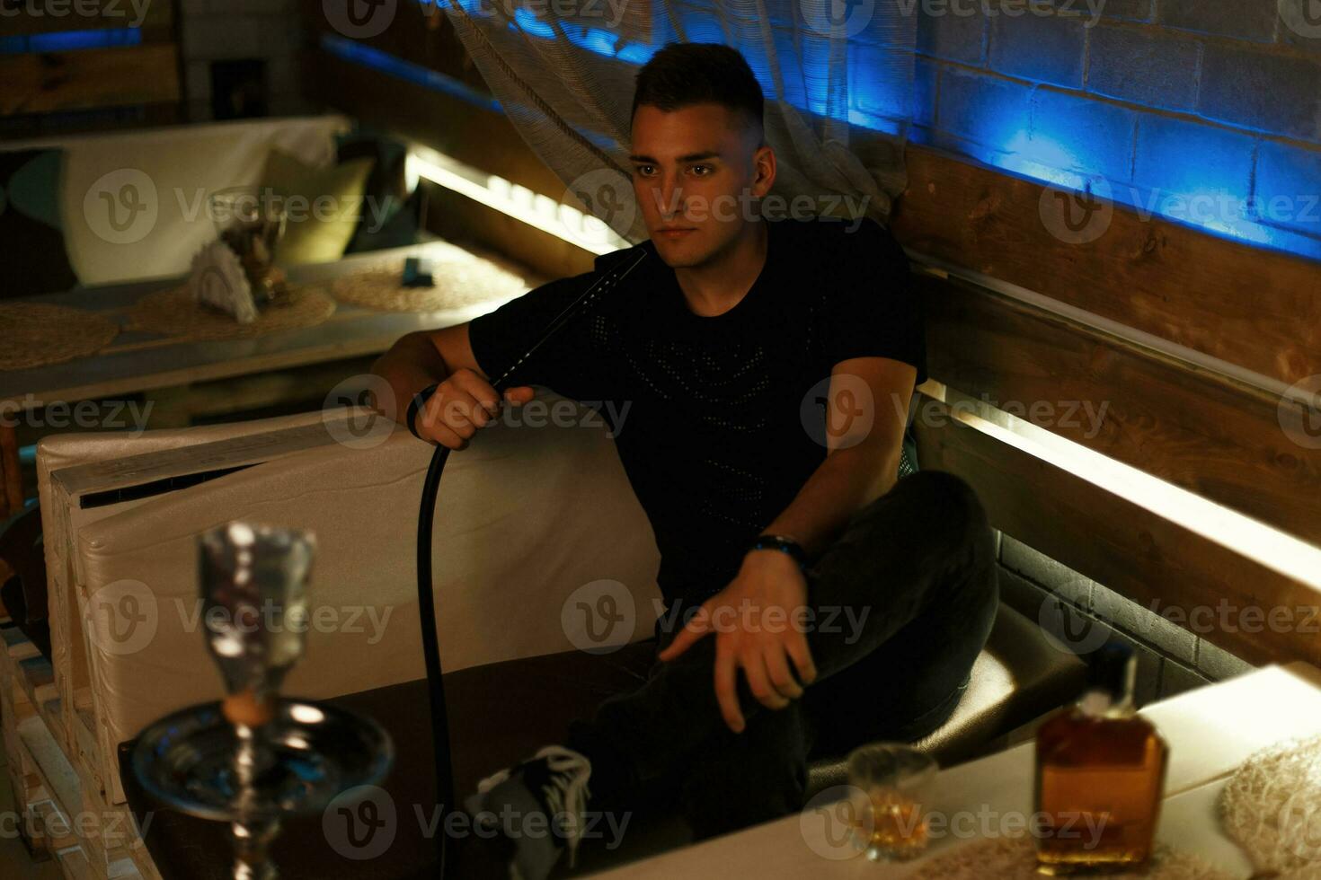 bonito hipster homem relaxante dentro a bar. homem fuma uma cachimbo de água. foto