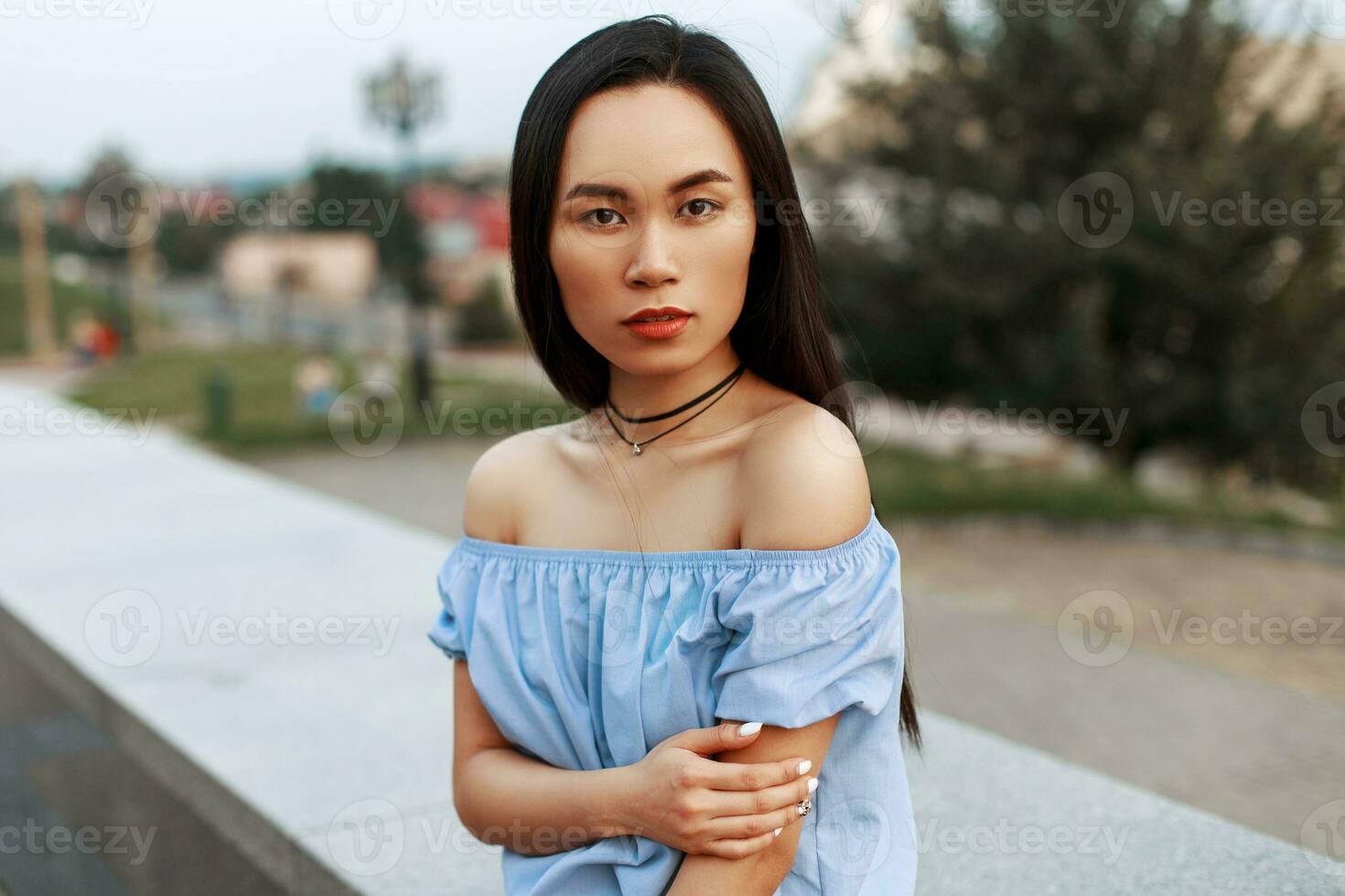 à moda ásia lindo menina dentro azul blusa posando em a fundo do a cidade. foto