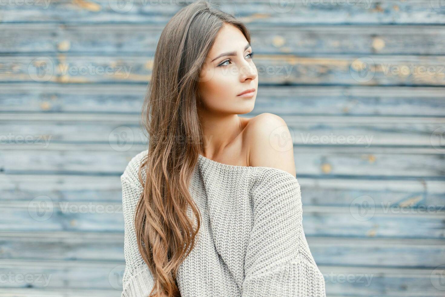 lindo jovem mulher com a Penteado dentro uma vintage cinzento suéter perto a azul parede foto