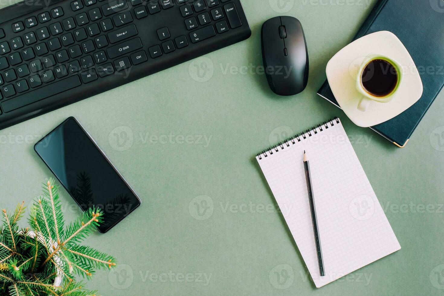 a sobrecarga trabalhos lugar. teclado, rato, Móvel telefone, café copo e bloco de anotações em uma verde fundo. topo Visão foto