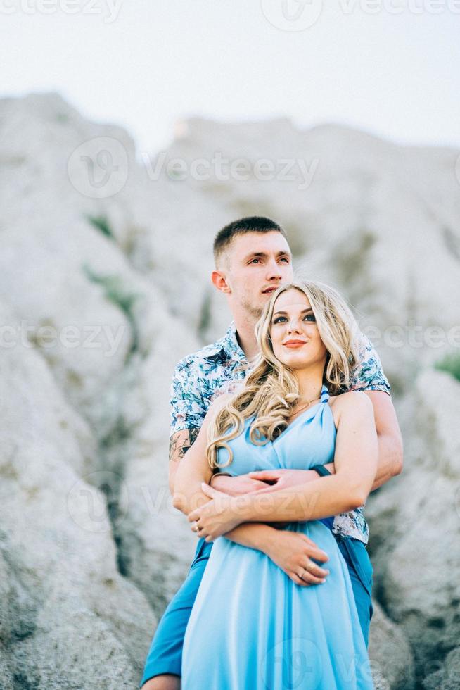 garota loira com um vestido azul claro e um cara com uma camisa leve em uma pedreira de granito foto