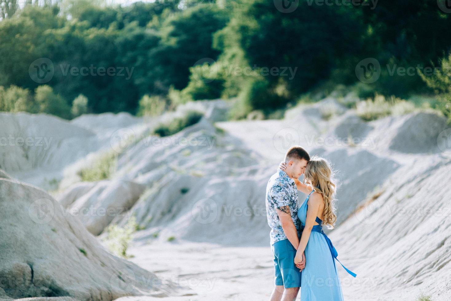 garota loira com um vestido azul claro e um cara com uma camisa leve em uma pedreira de granito foto