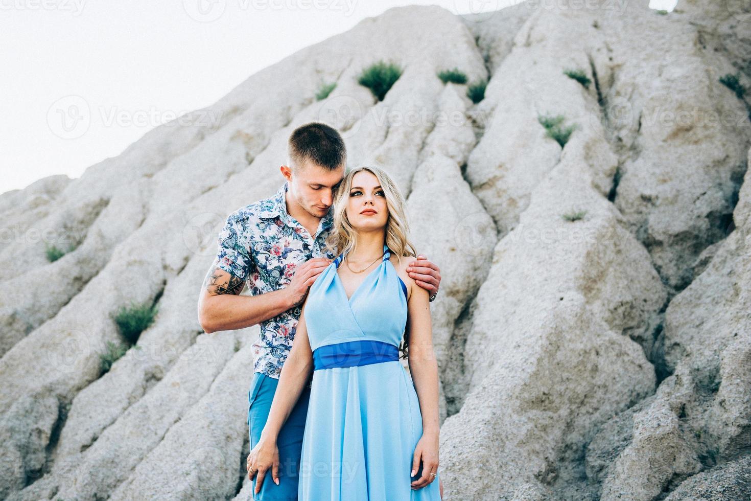 garota loira com um vestido azul claro e um cara com uma camisa leve em uma pedreira de granito foto