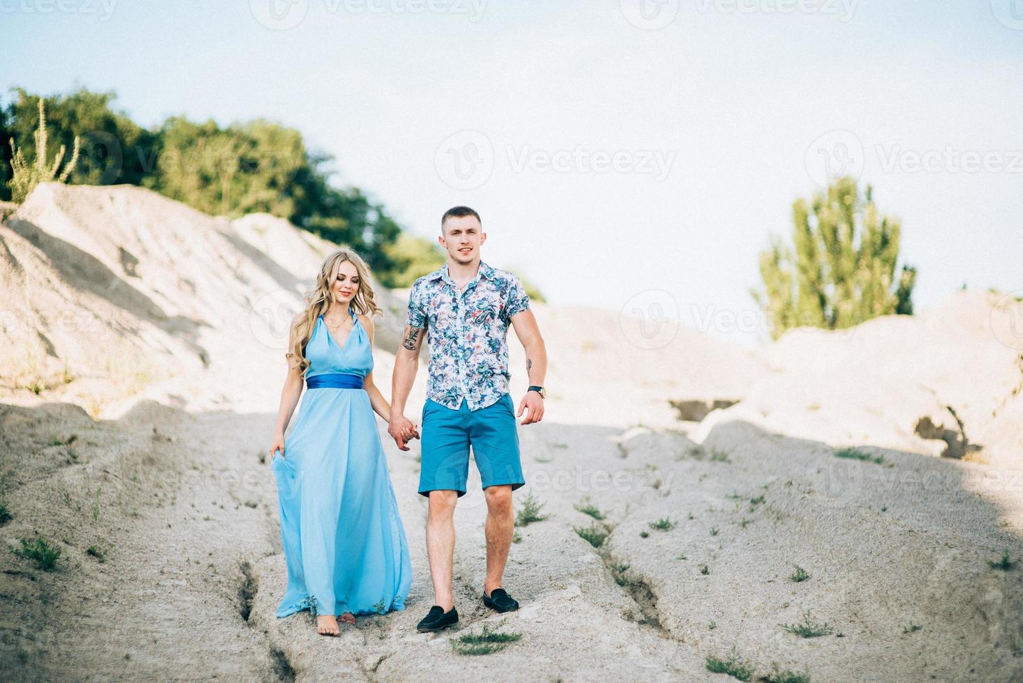 garota loira com um vestido azul claro e um cara com uma camisa leve em uma pedreira de granito foto