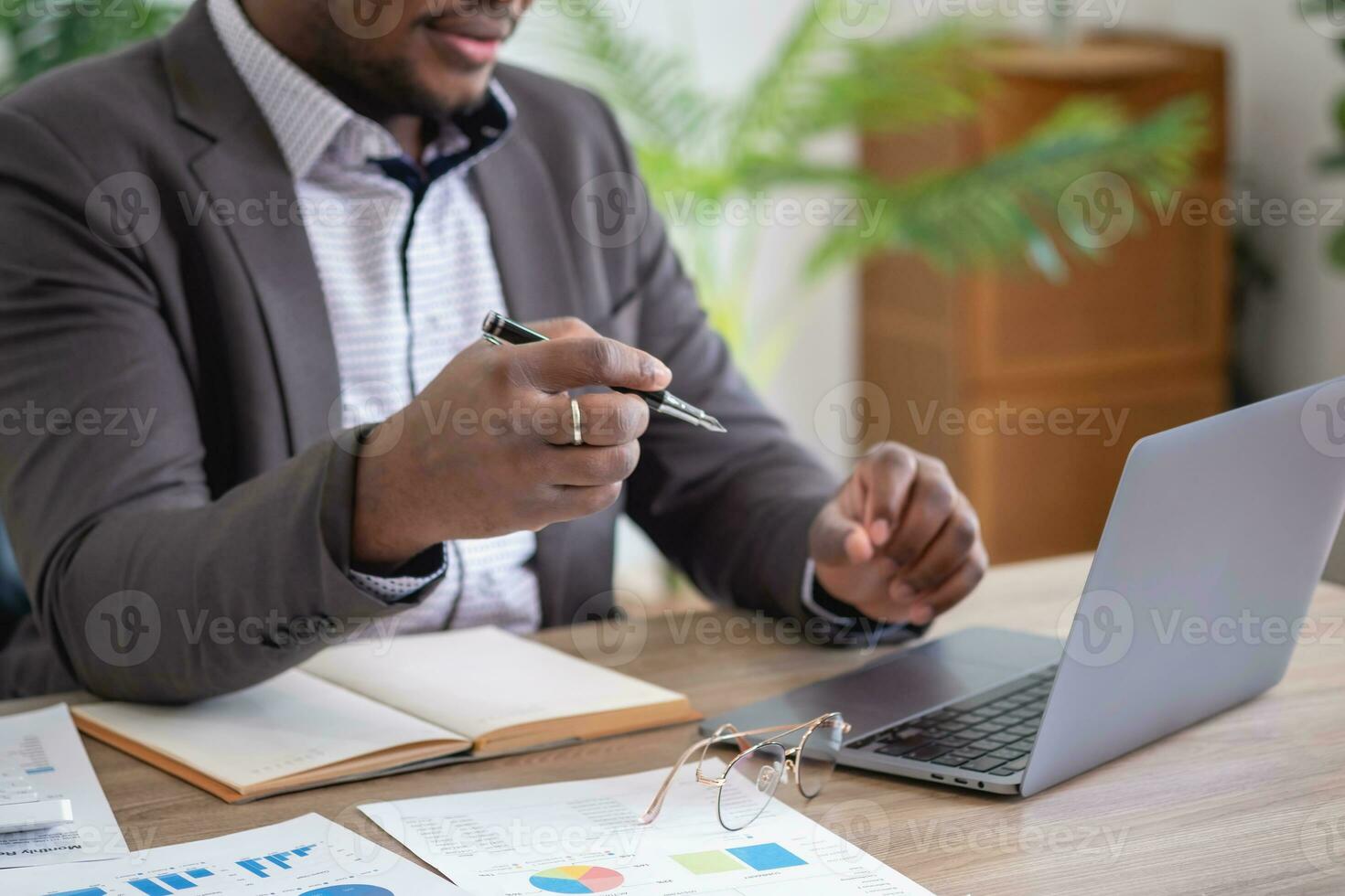 africano americano homem de negocios analisando computador portátil gráfico papelada dentro escritório segurando documentos preparando portfólio análise relatório Preto masculino analista fazendo papelada dentro a local de trabalho usando a computador. foto