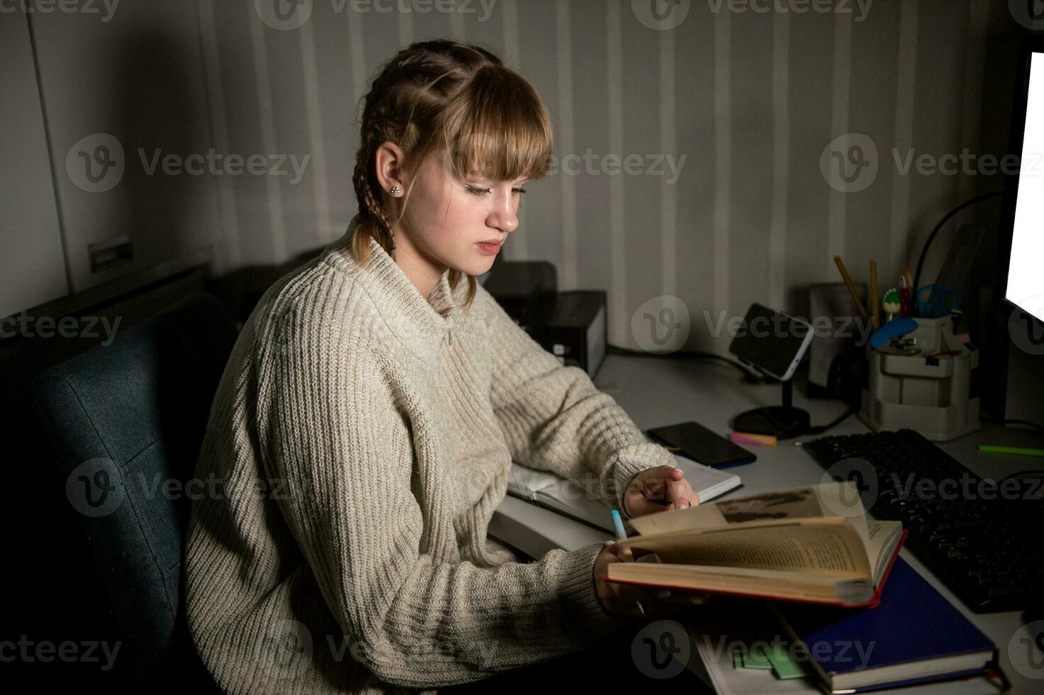 a sobrecarregado aluna senta às noite com uma livro. faço notas dentro uma caderno dentro a escuro. foto