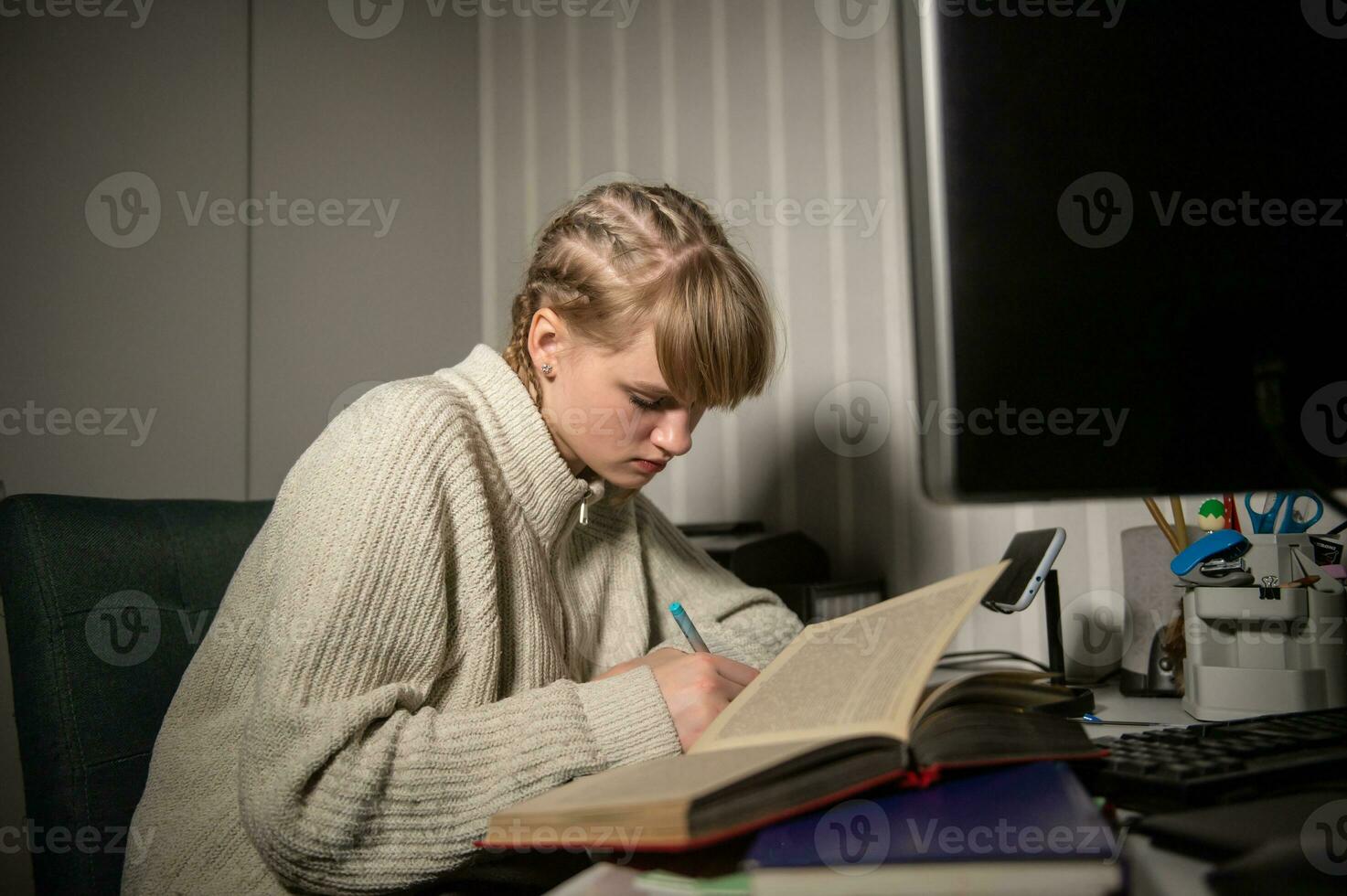 excesso de trabalho e insônia a partir de em processamento às noite. lendo livro às noite dentro a Sombrio perto a computador foto