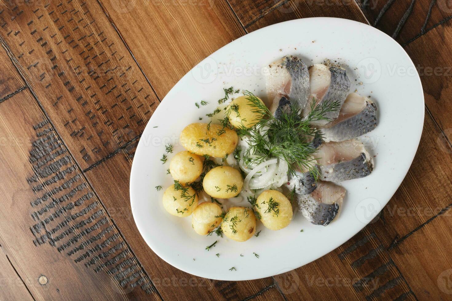 arenque peixe com jovem batatas bolas em uma branco prato foto