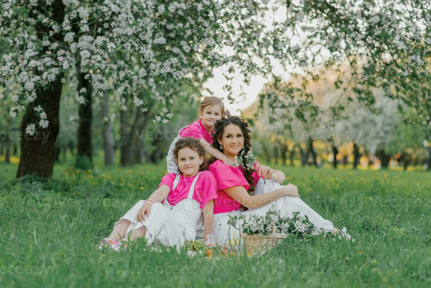fofa mãe e dois filhas estão tendo uma piquenique dentro a Primavera jardim. ao ar livre atividade. doce momentos família foto