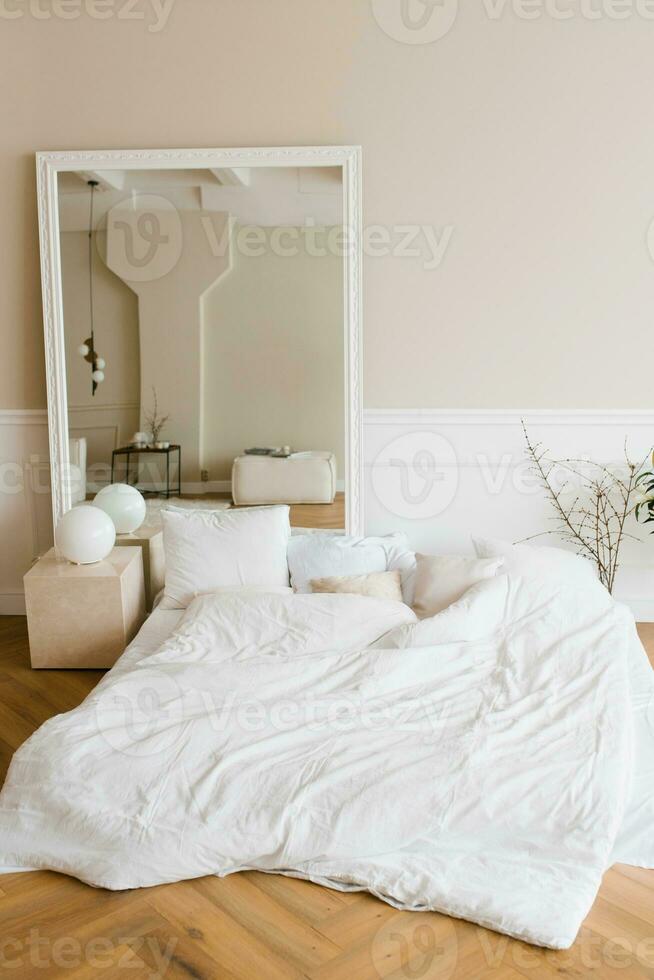 interior do quarto em estilo escandinavo. uma cama no chão com lençóis e travesseiros brancos foto