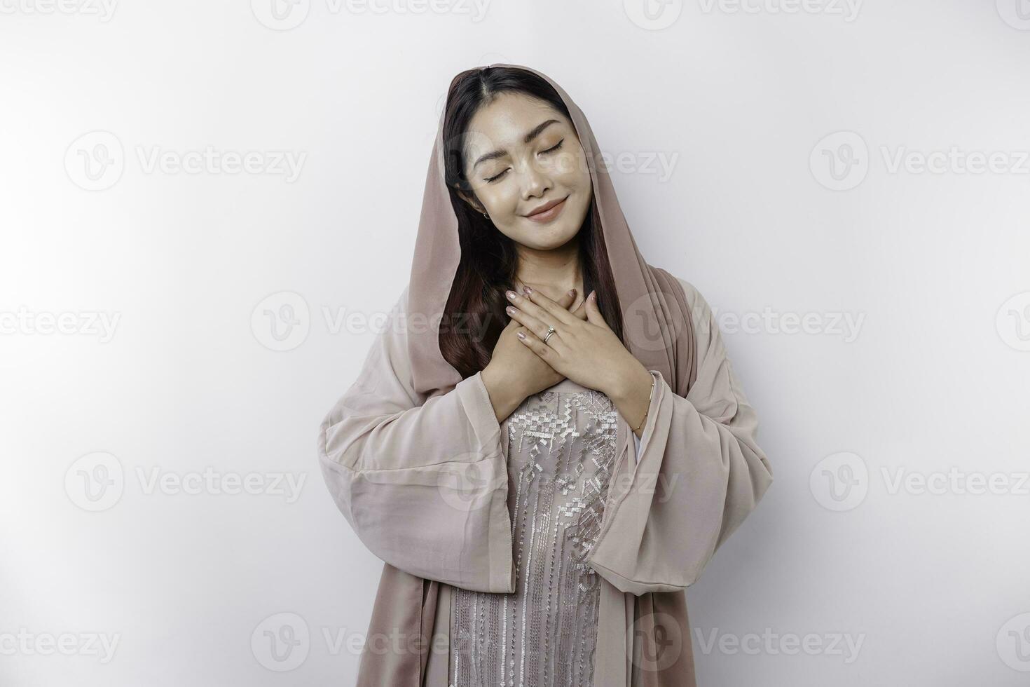 feliz atento grato jovem ásia muçulmano mulher com dela mão em dela peito sorridente isolado em branco fundo foto