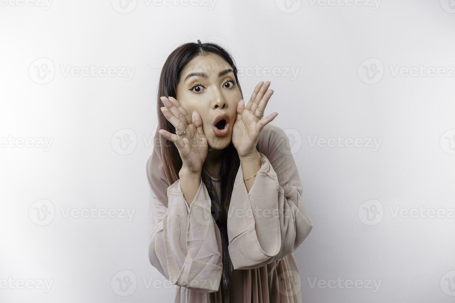 jovem lindo ásia muçulmano mulher vestindo uma lenço de cabeça gritando e gritando alto com uma mão em dela boca. comunicação conceito. foto