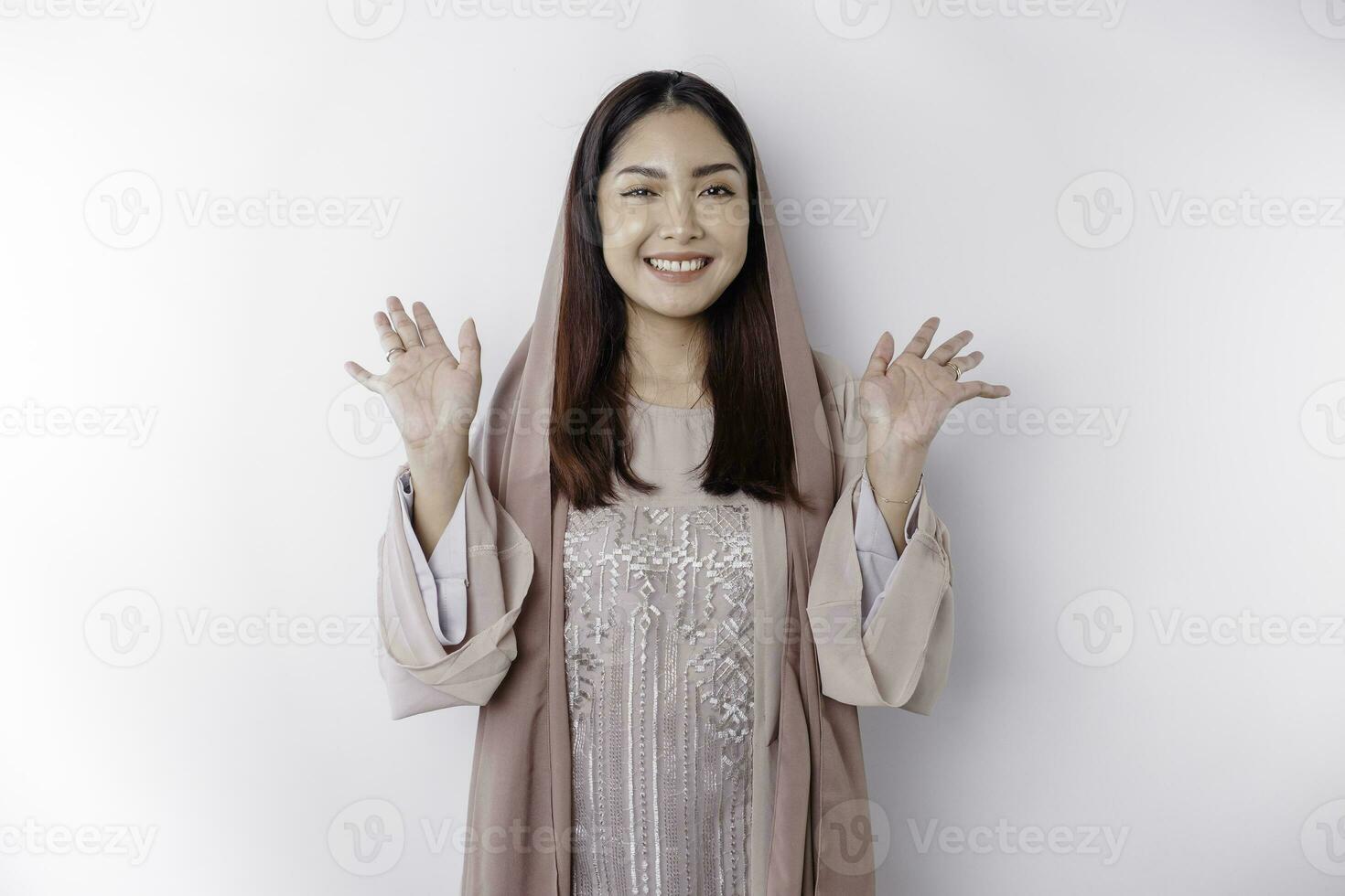 retrato do uma jovem lindo ásia muçulmano mulher vestindo uma lenço de cabeça gesticulando eid Mubarak cumprimento foto