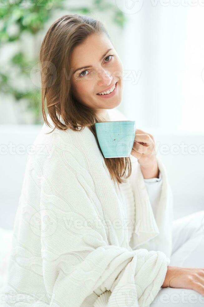 jovem agradável mulher dentro cama com café ou chá caneca foto