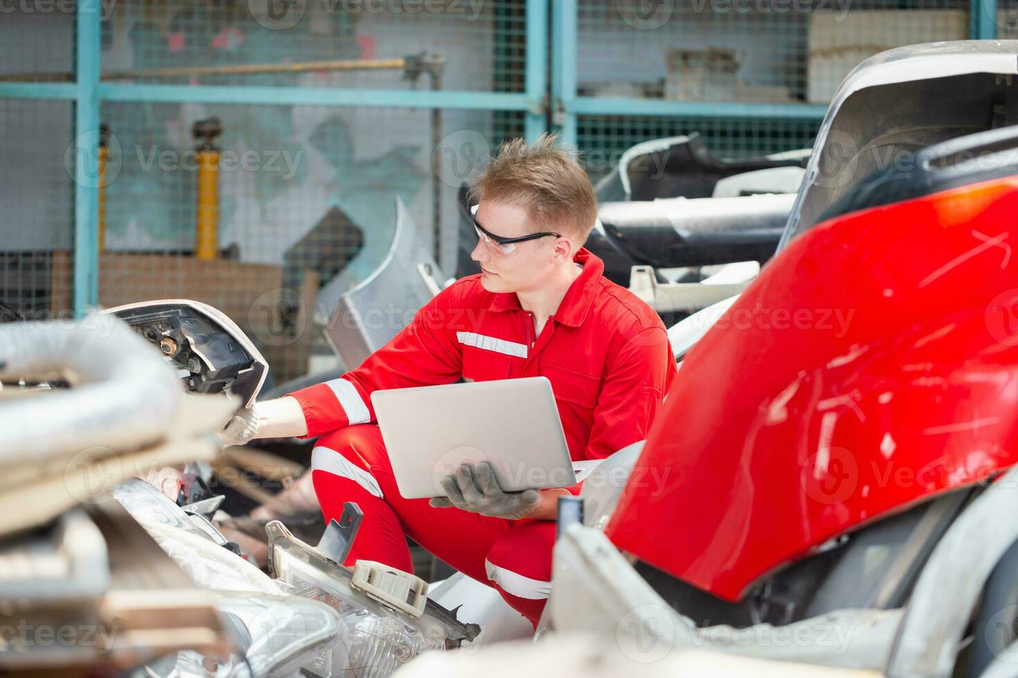 mecânico homem inspecionando carro partes estoque em computador portátil computador enquanto trabalhando dentro garagem armazém, jovem mecânico com computador portátil dentro auto reparar fazer compras foto