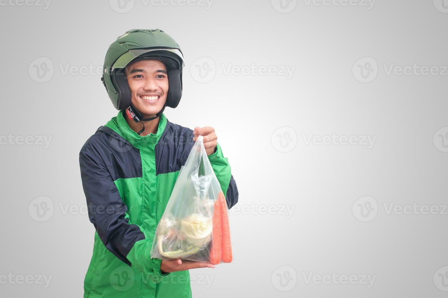 retrato do ásia conectados Táxi motorista vestindo verde Jaqueta e capacete entregando a legumes a partir de tradicional mercado e apontando com dedo. isolado imagem em branco fundo foto