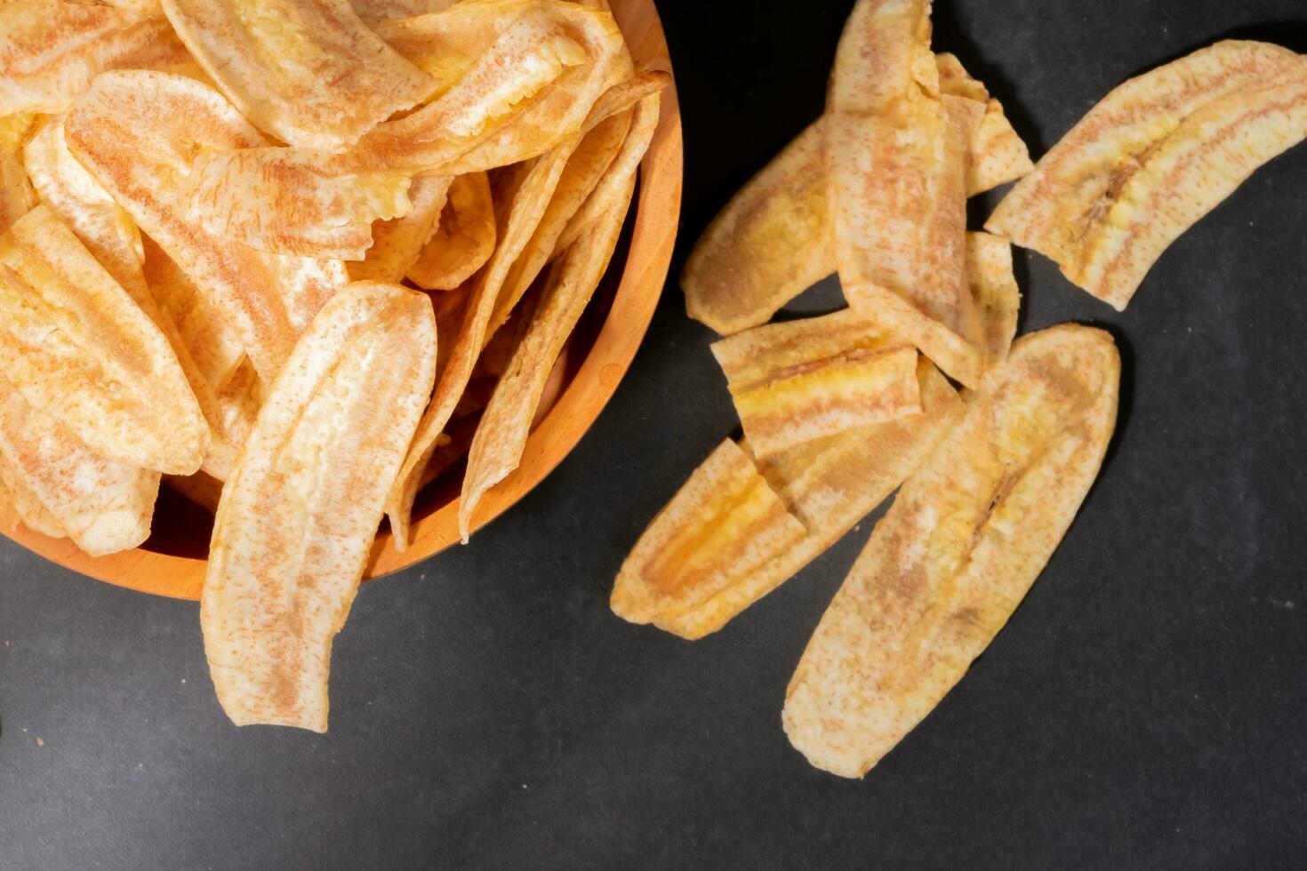 banana salgadinhos com uma doce e salgado gosto fez a partir de frito cru bananas dentro uma de madeira tigela. tradicional lanches foto