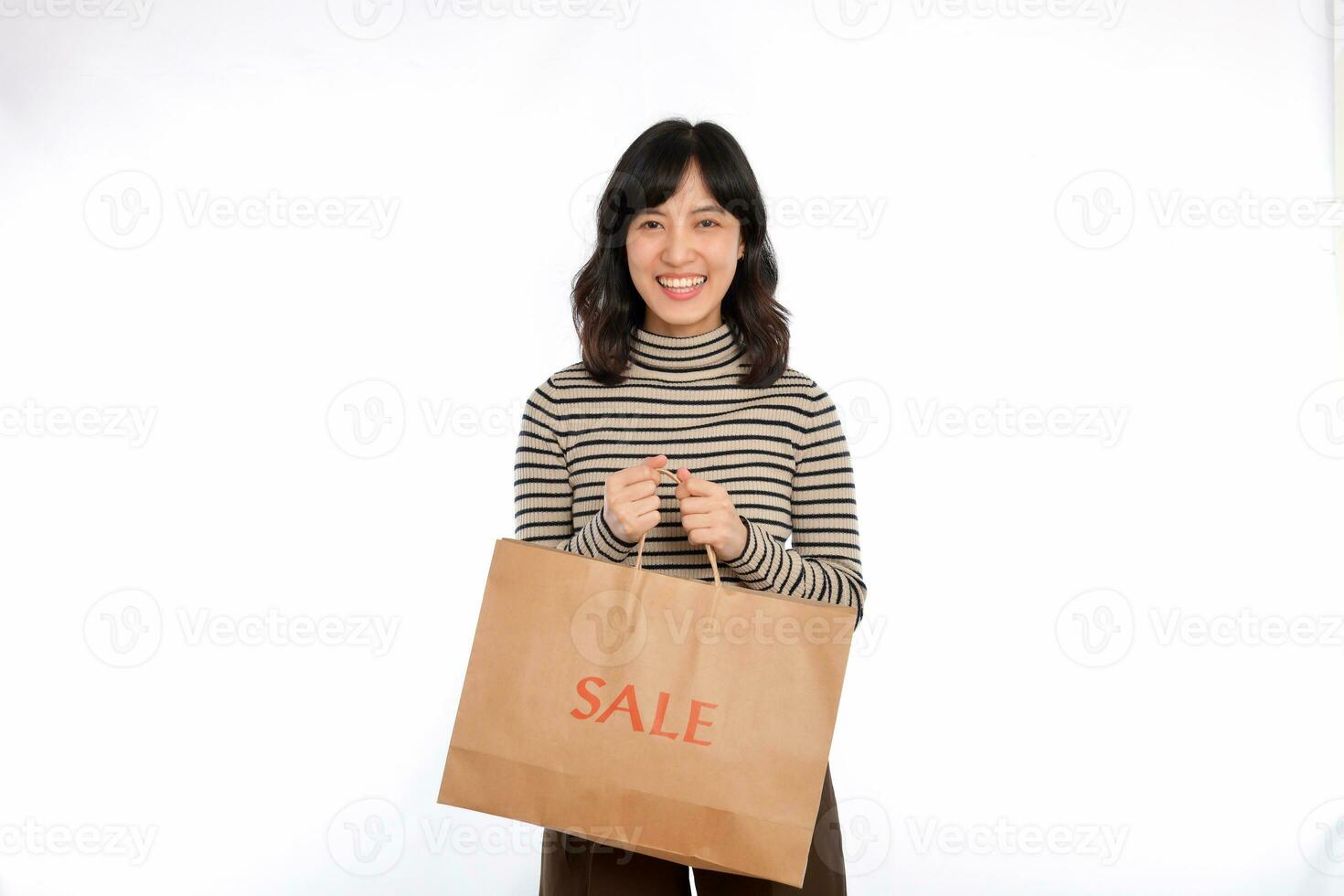 feliz jovem ásia mulher casual uniforme segurando compras papel saco isolado em branco fundo. compras desconto conceito foto