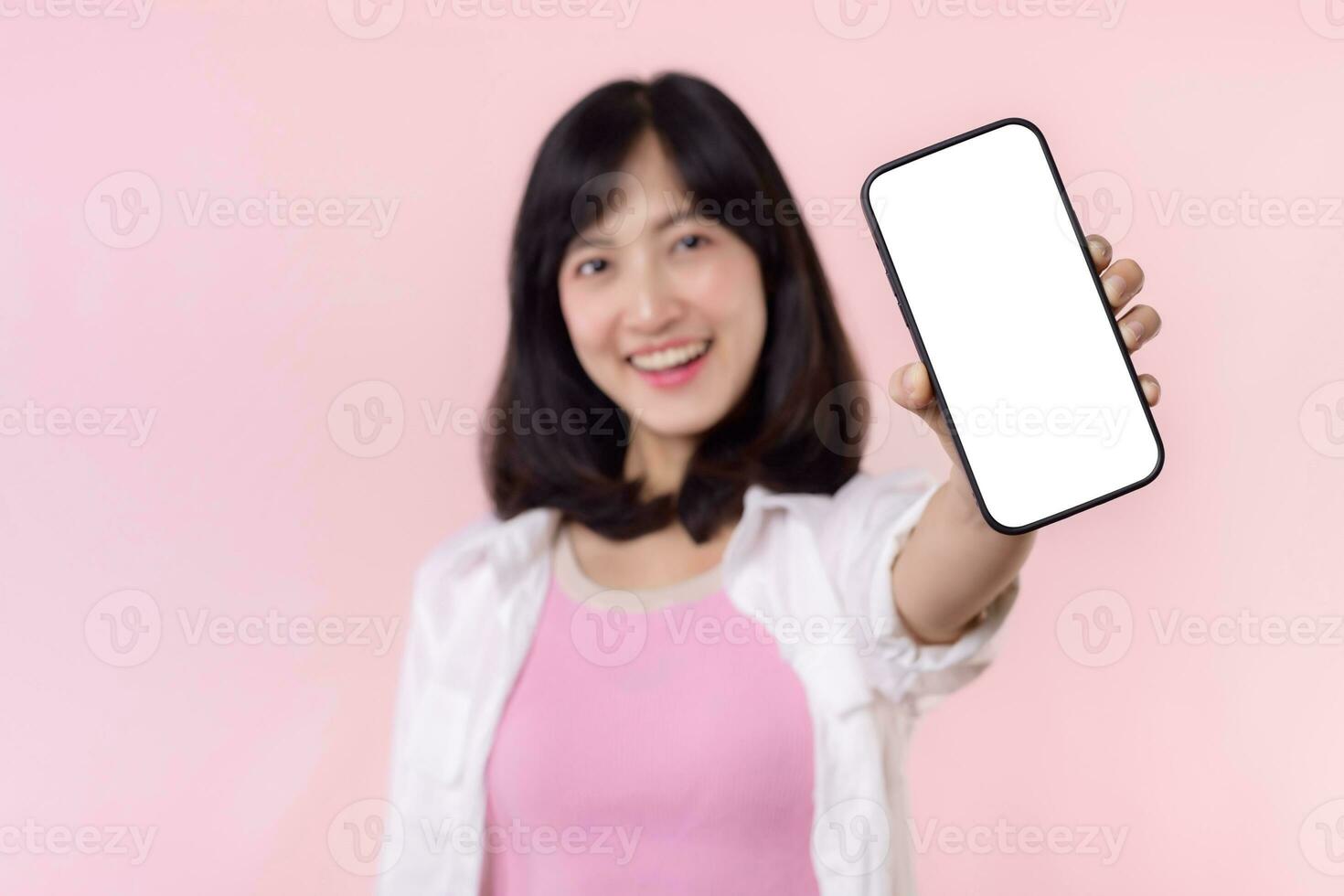 feliz sorridente jovem ásia mulher recomendando mostrando Novo inscrição ou Móvel anúncio, brincar Smartphone modelo bandeira isolado em Rosa fundo. colagem em branco tela digital Móvel dispositivo. foto