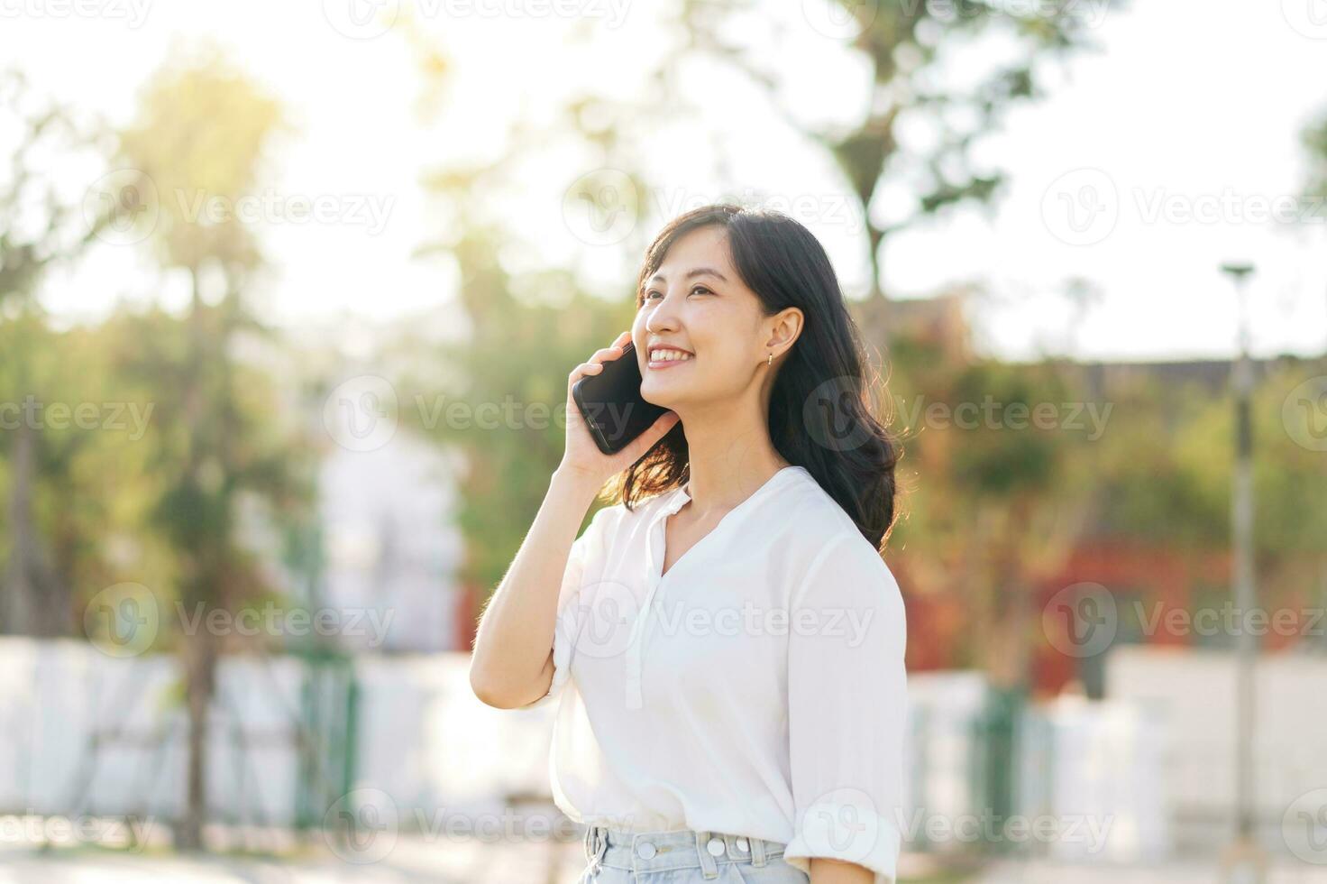 retrato lindo jovem ásia mulher com inteligente Móvel telefone por aí ao ar livre natureza Visão dentro uma ensolarado verão dia foto