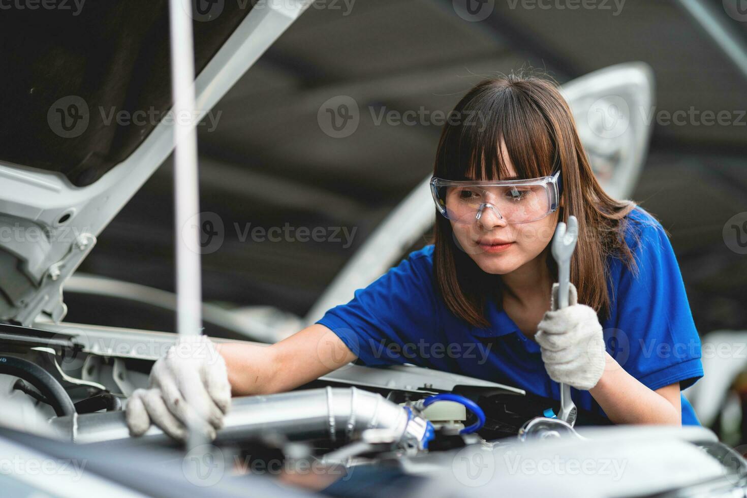 conceito de reparo automático. mecânico de carro de mulher asiática vestindo camisa aquarela na garagem. feliz mecânico feminino no centro de reparação de automóveis foto