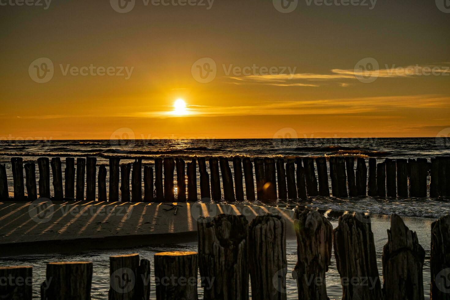 colorida pôr do sol sobre a polonês báltico mar com Sombrio céu nuvens e quebra-mar foto