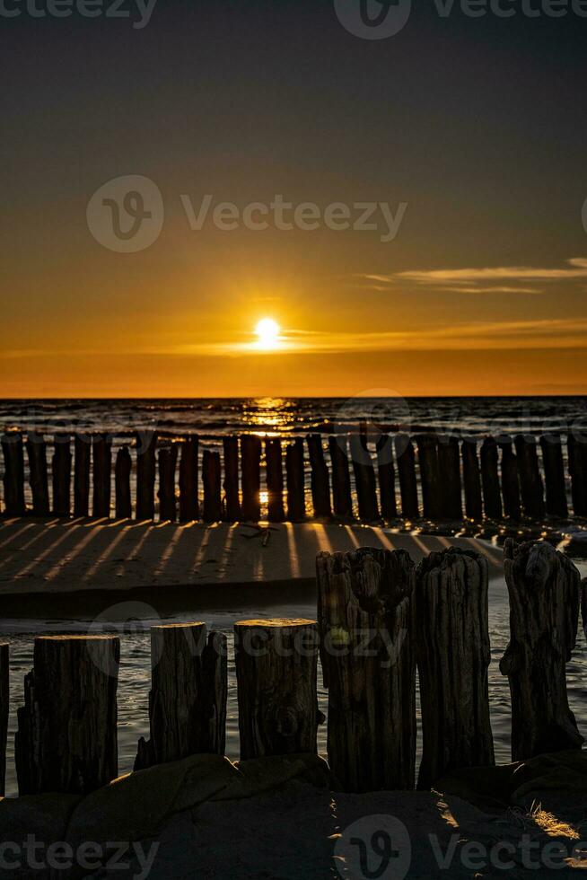 colorida pôr do sol sobre a polonês báltico mar com Sombrio céu nuvens e quebra-mar foto