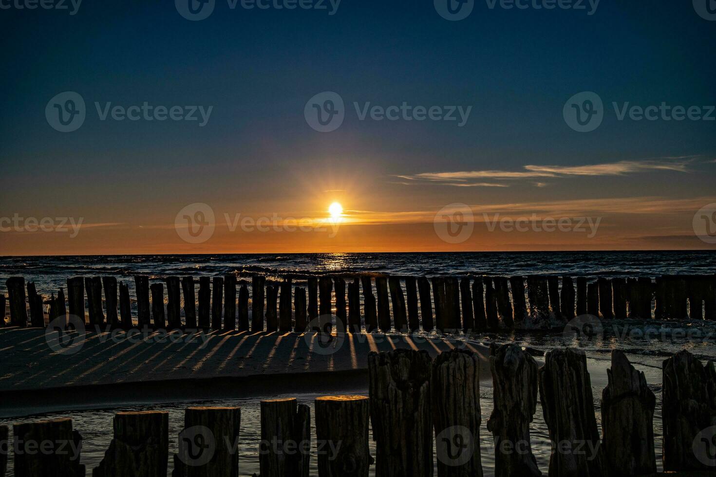 colorida pôr do sol sobre a polonês báltico mar com Sombrio céu nuvens e quebra-mar foto