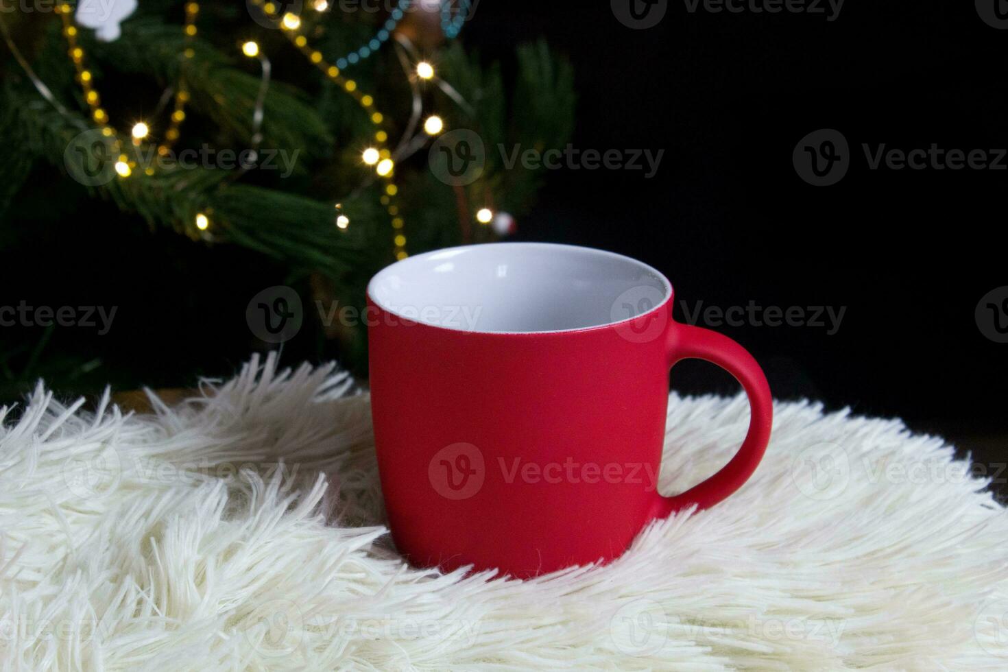 em branco vermelho caneca com Natal árvore em fundo, tapete chá ou café copo com Natal e Novo ano decoração, horizontal zombar acima com cerâmico caneca para quente bebidas, vazias presente impressão modelo foto