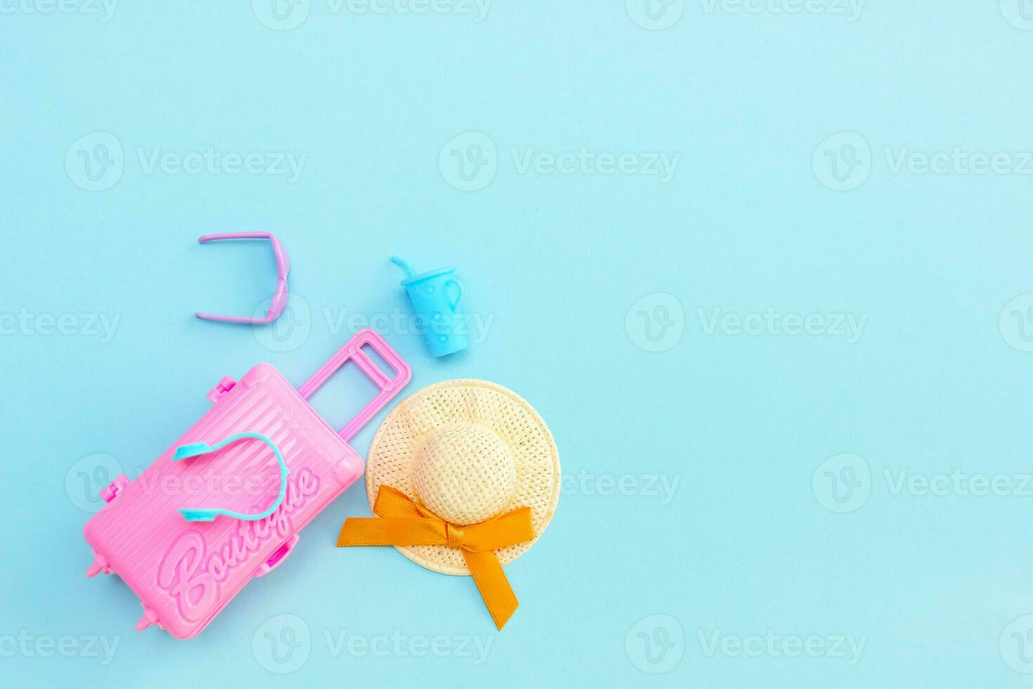 brinquedo Rosa mala, oculos de sol, Palha chapéu e vidro com coquetel em azul fundo com cópia de espaço, período de férias conteúdo foto