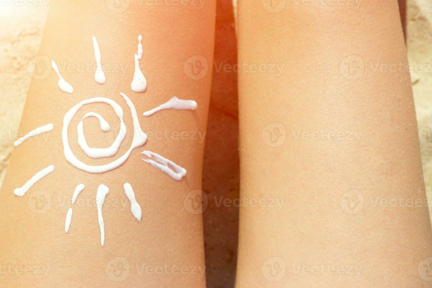 mulher banhos de sol em a de praia com uma desenhando do Sol em dela perna com creme foto