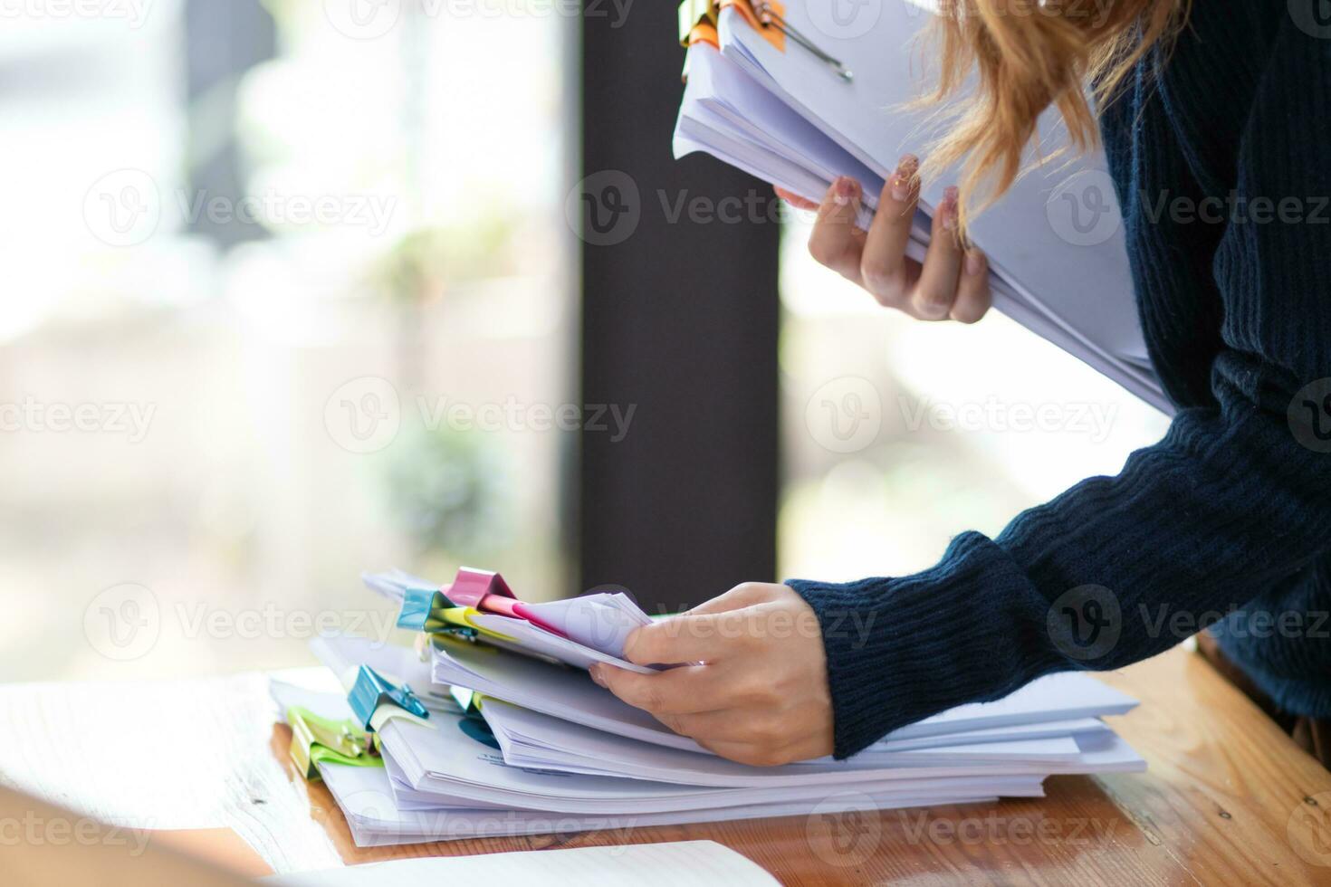 empresária mãos trabalhando em pilhas do papel documentos para procurar e Reveja documentos empilhado em mesa antes enviando eles para borda do diretores para usar corrigir documentos dentro encontro com homem de negocios foto