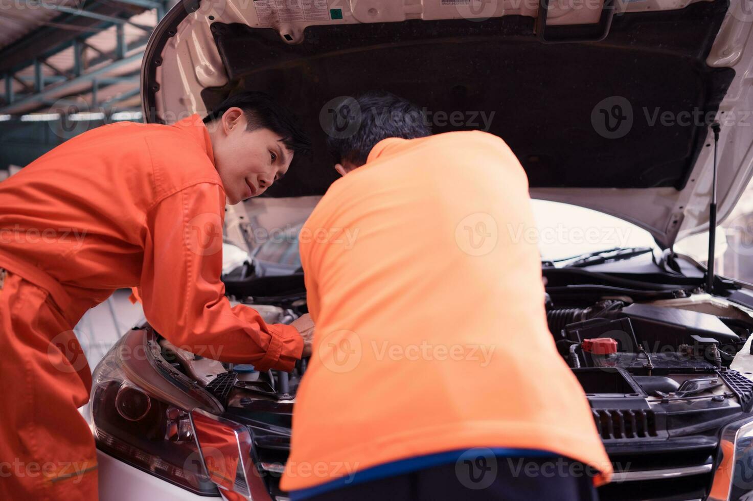 ambos do auto mecânica estão inspecionando a motor do uma clientes carro ser trouxe dentro para reparar às uma garagem. foto