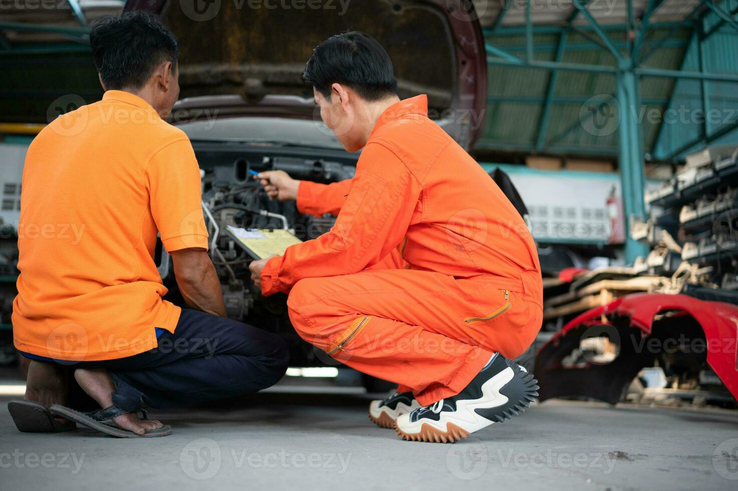 ambos do auto mecânica estão inspecionando a motor do uma clientes carro ser trouxe dentro para reparar às uma garagem. foto