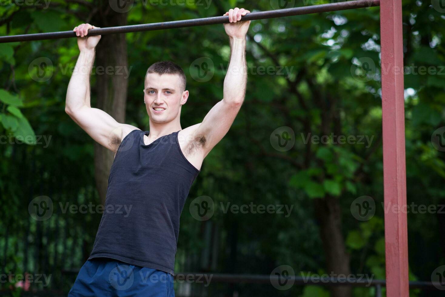 Forte homem fazendo pull-ups em uma Barra ao ar livre foto