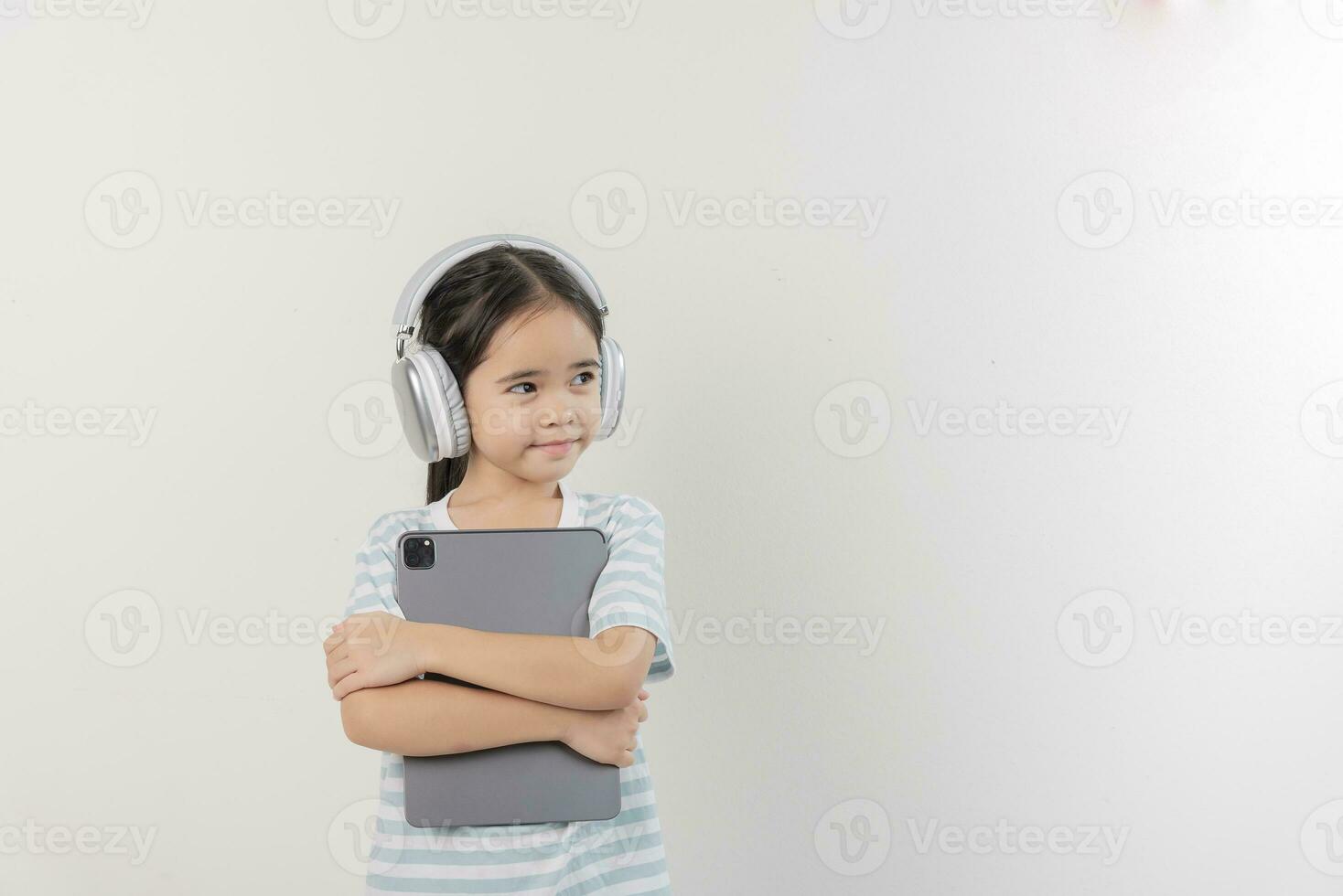 sorridente pequeno menina tenso e segurando uma tábua com fone de ouvido foto