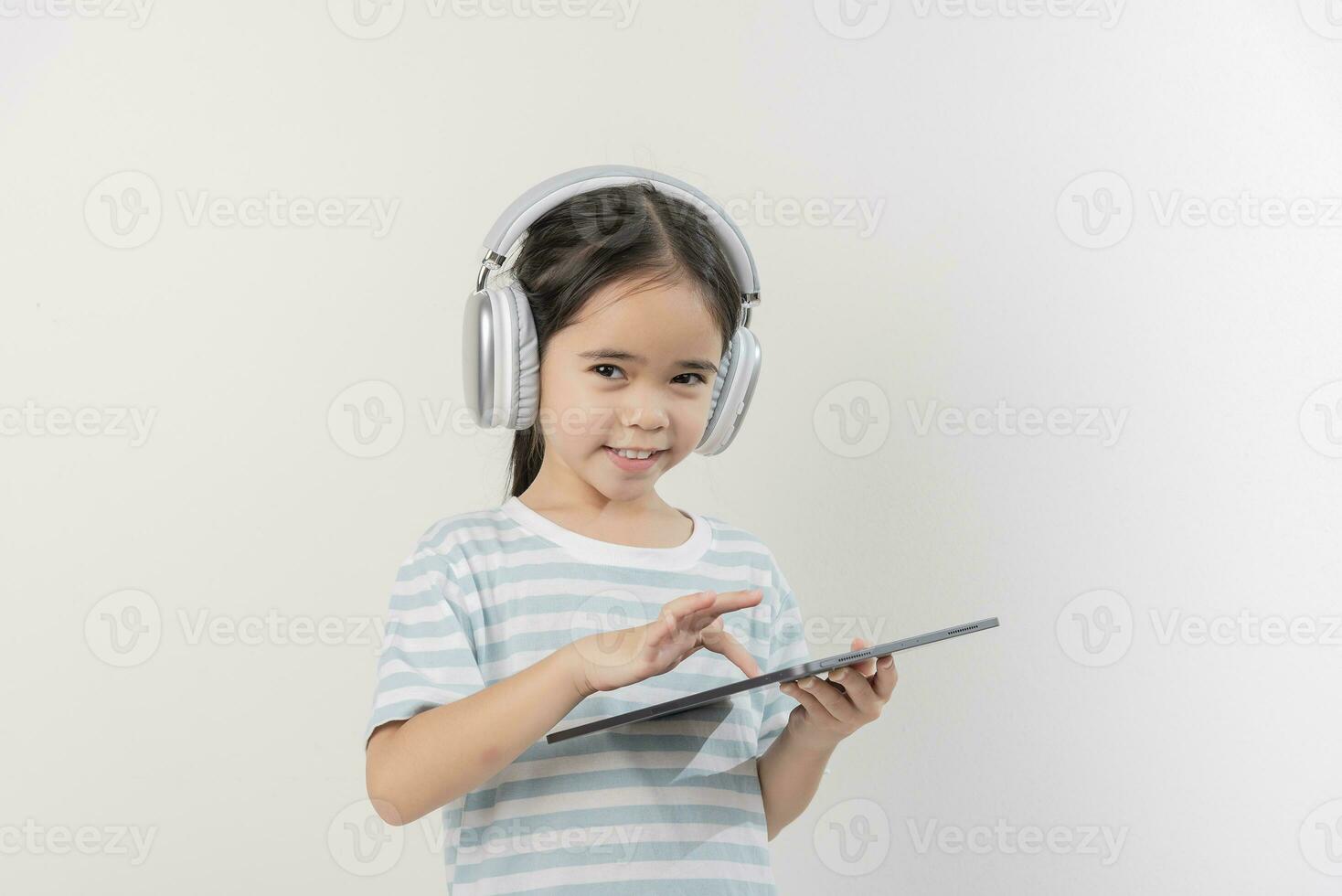 sorridente pequeno menina tenso e segurando uma tábua com fone de ouvido foto