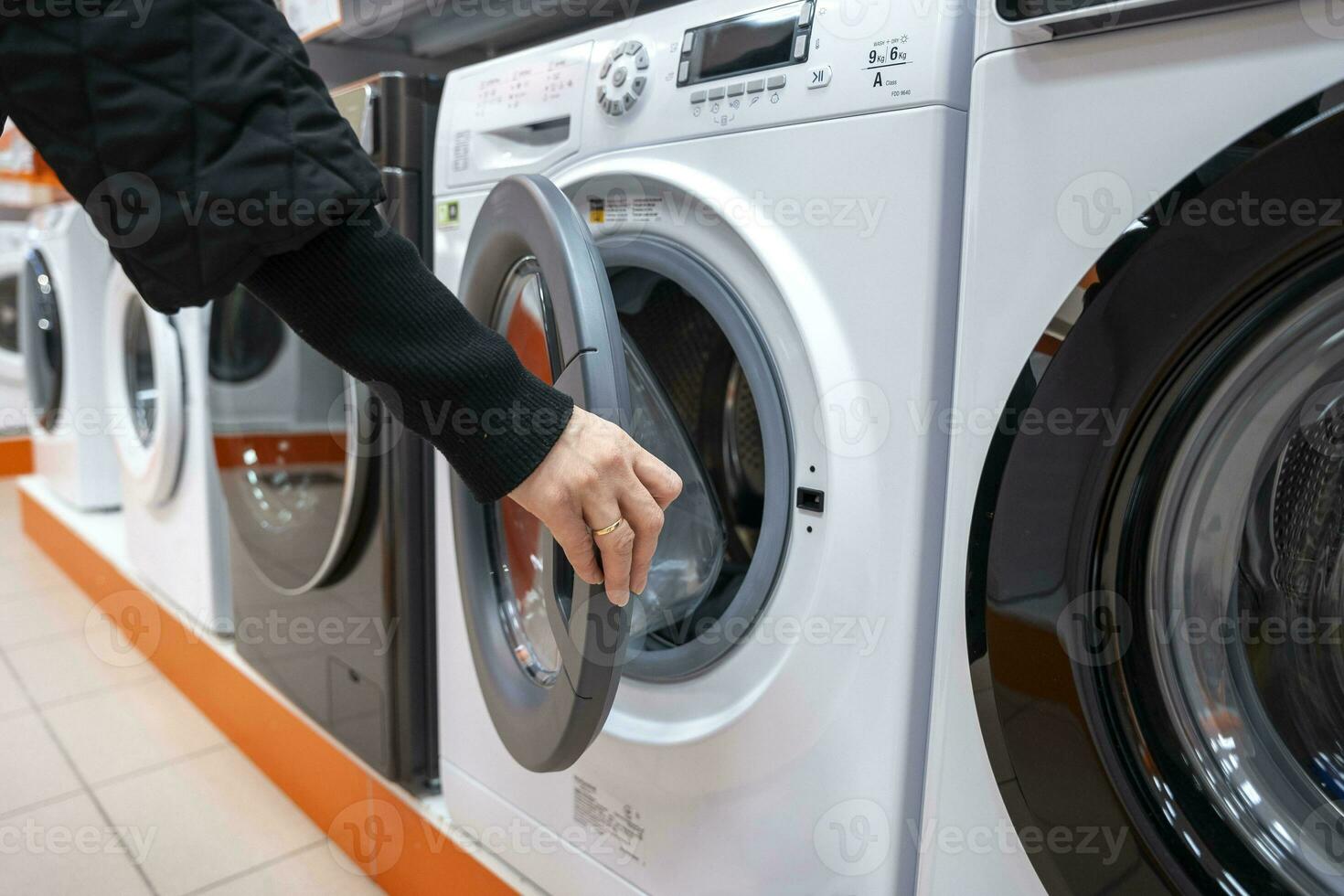 mulher escolhe uma montado na frente lavando máquina dentro casa utensílio loja foto
