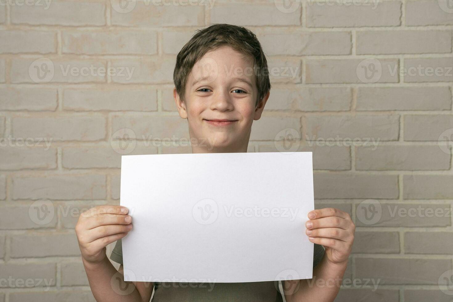 uma alegre sorridente criança de 5 anos europeu Garoto detém a esvaziar poster acima dele cabeça foto