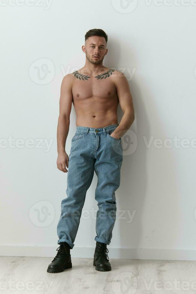 desportivo sexy muscular bonito nu homem detém mão em jeans parece às Câmera posando isolado em sobre branco estúdio fundo. legal moda oferecer. modelo tiro para de Anúncios. cópia de espaço. cheio corpo retrato foto