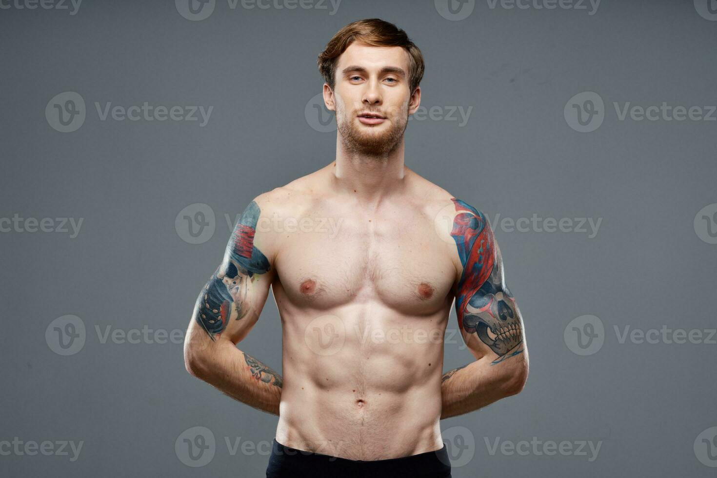 desportivo homem com tatuagens em dele braços bombeado acima pressione macho cinzento fundo foto