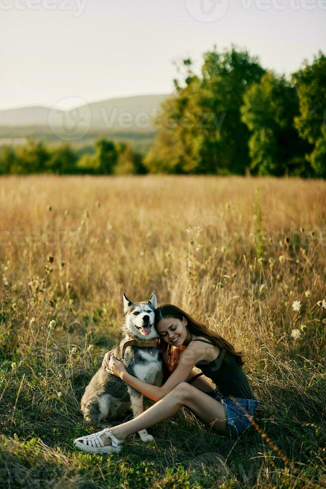 mulher sentado dentro campo com dachshund cachorro sorridente enquanto gastos Tempo dentro natureza com amigo cachorro dentro outono às pôr do sol enquanto viajando foto