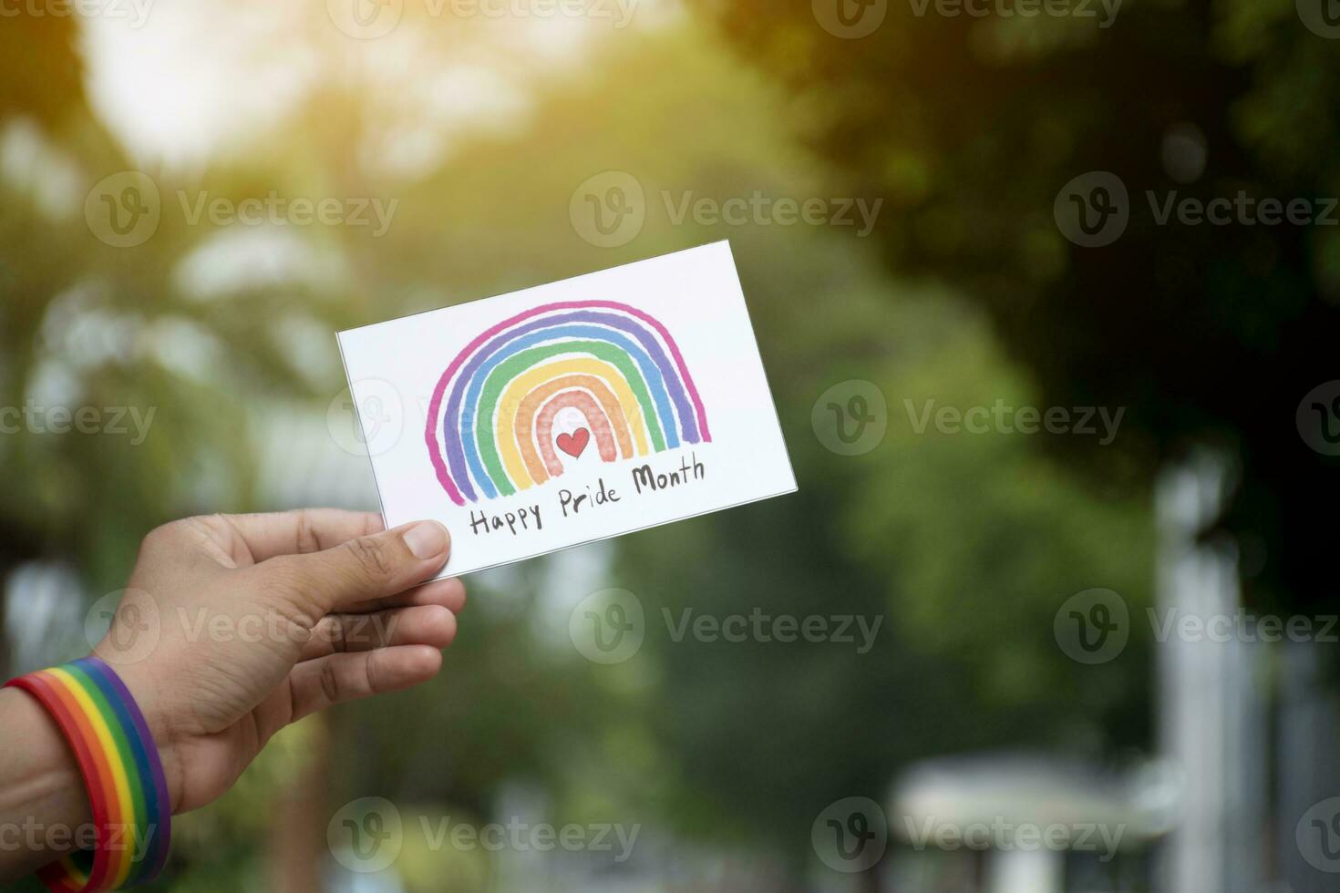 'feliz orgulho mês' cartão segurando dentro mão que tem arco Iris pulseira por aí isto, conceito para cumprimento todos pessoas para estar feliz dentro a lgbtq eventos por aí a mundo dentro orgulho mês. foto