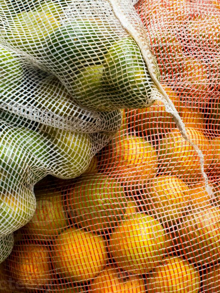 fechar acima do bolsas preenchidas com laranjas e limões foto