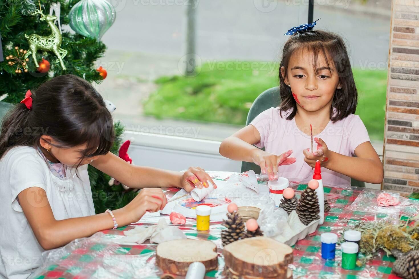 dois pequeno irmãs tendo Diversão enquanto fazer Natal natividade trabalhos manuais com às casa - real família foto