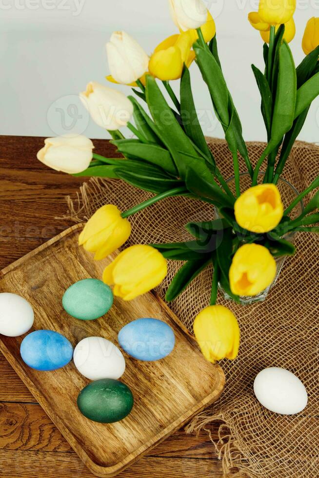 colorida ovos em uma de madeira bandeja uma ramalhete do amarelo flores Páscoa ressurreição do Cristo foto