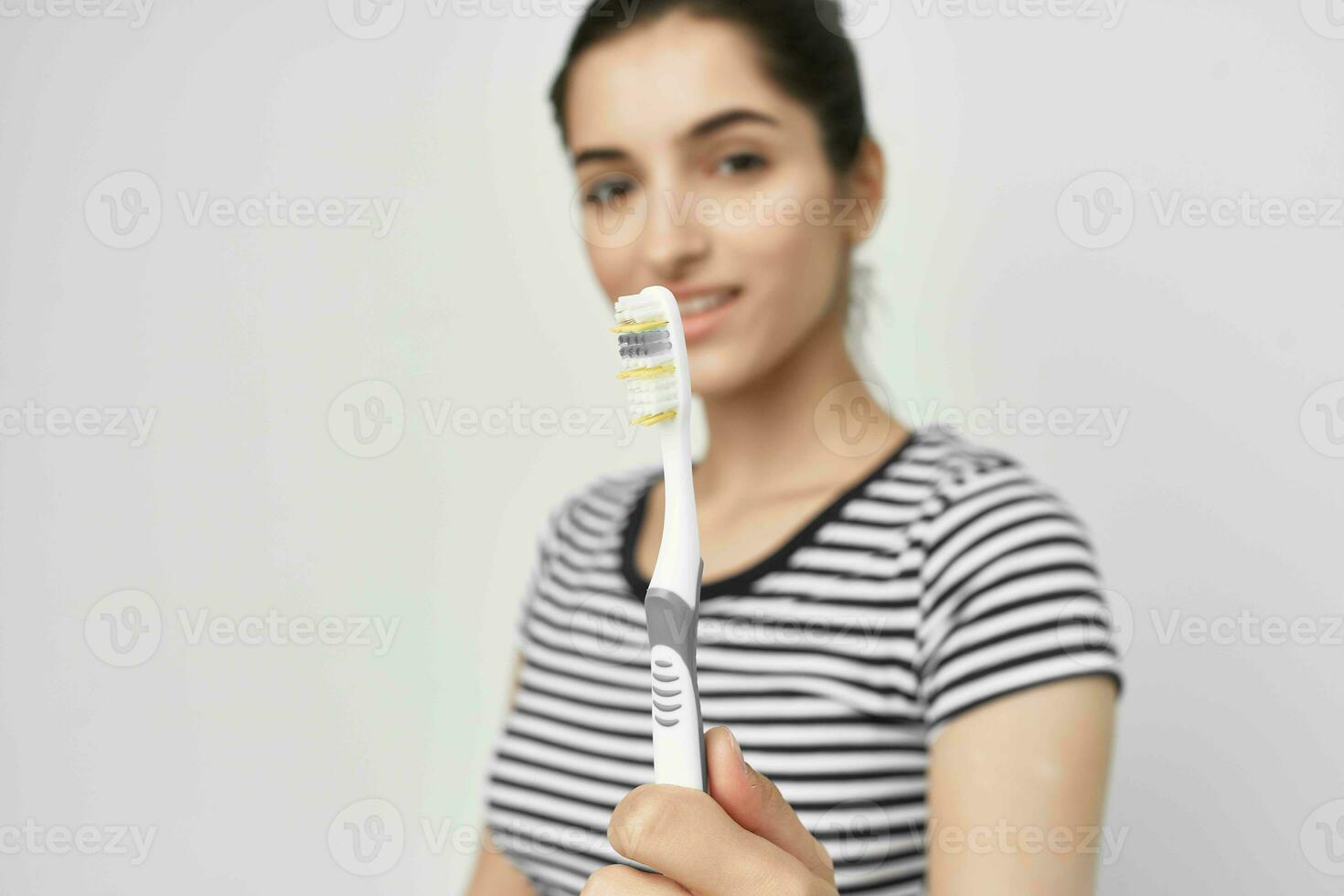 alegre mulher escova seu dentes com uma escova de dente luz fundo foto